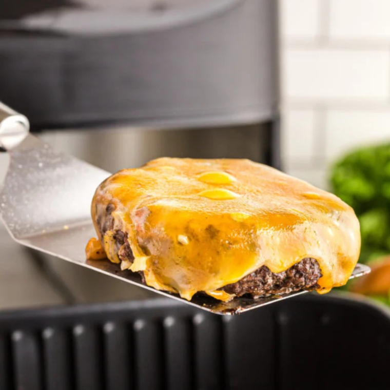 Cheeseburger on spatula, fully cooked, and cheese melted.