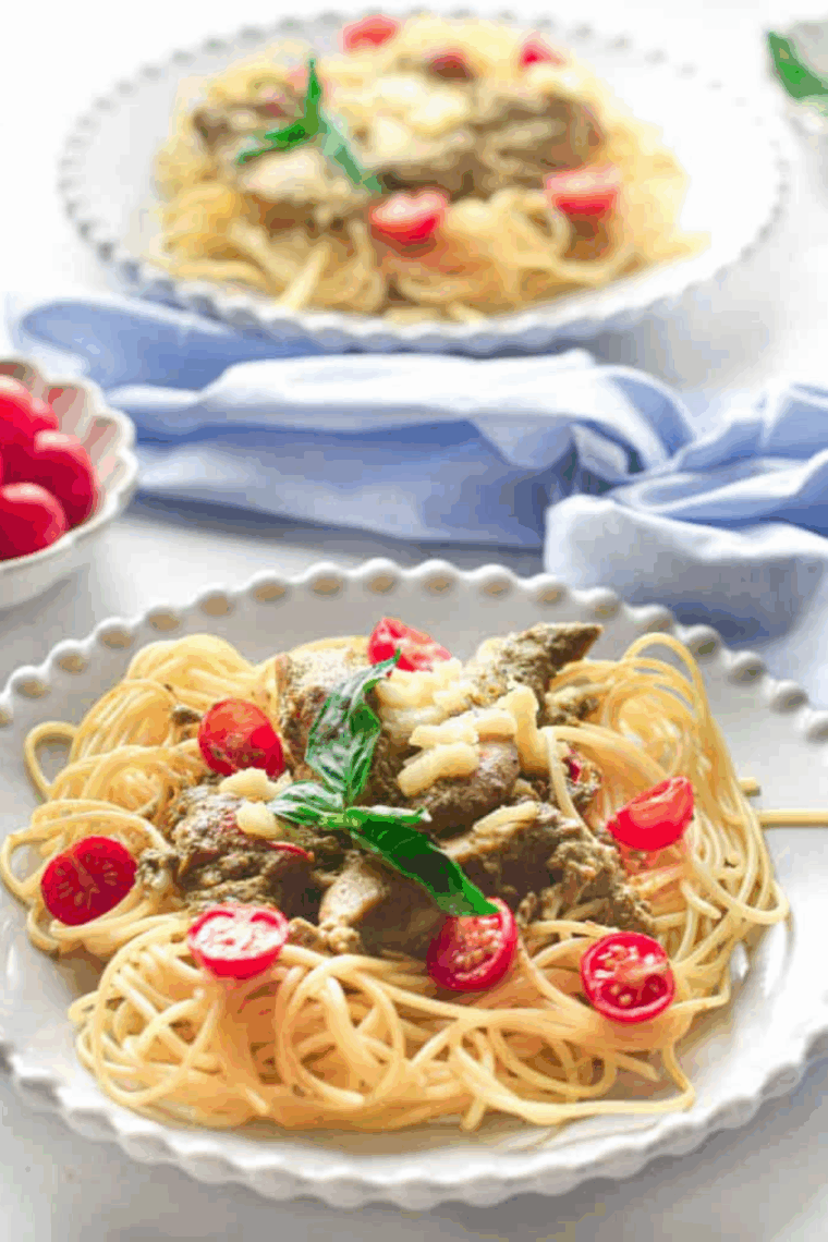 Bowl of Instant Pot pesto chicken pasta with tender chicken, pasta, and creamy green pesto, garnished with Parmesan and fresh basil
