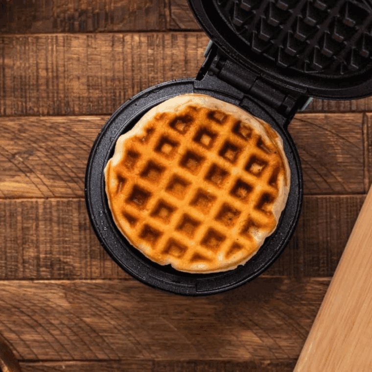 Pouring batter into waffle iron cooking golden waffles