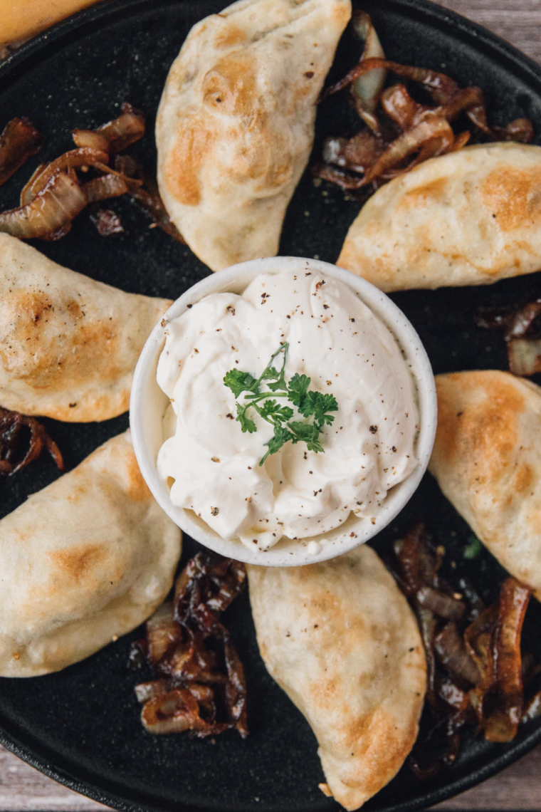 Golden homemade potato and cheese pierogies served with caramelized onions and a dollop of sour cream.