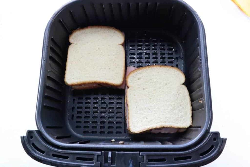 overhead: making grilled ham and cheese sandwich in air fryer basket