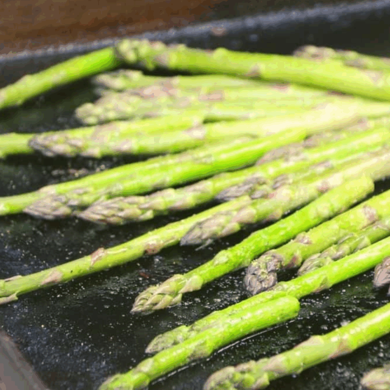 Fresh asparagus spears arranged evenly on a grill for a perfect tender-crisp sear.