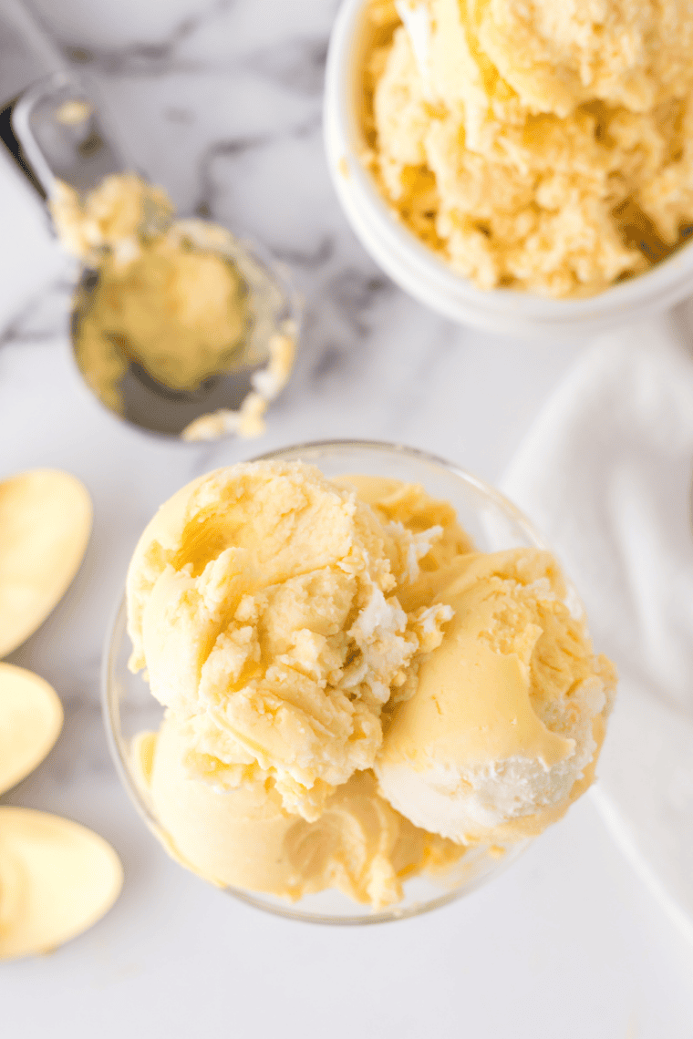 Bowl of creamy, sugar-free peach ice cream made in the Ninja Creami, garnished with fresh peach slices.