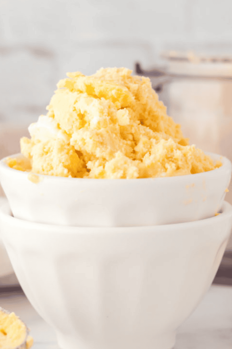 Bowl of sugar-free, creamy peach ice cream made in the Ninja Creami, topped with fresh peach slices.