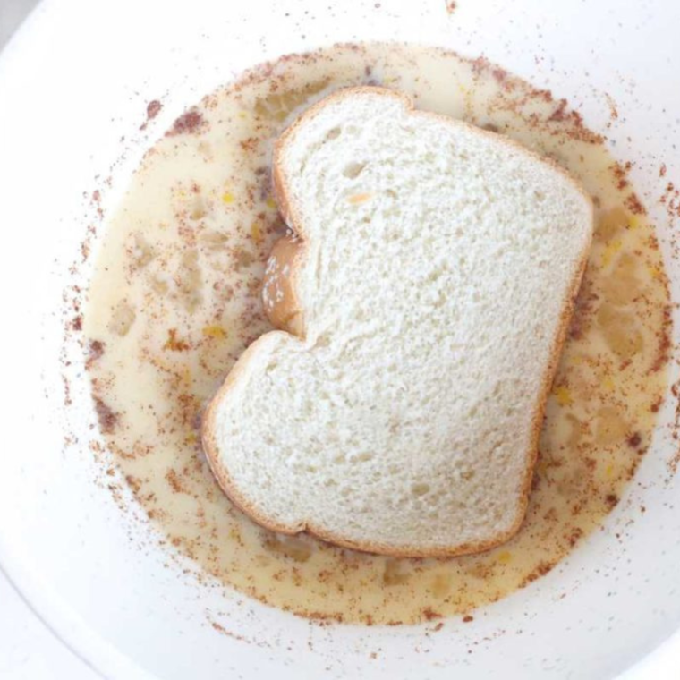 Placing bread slices into the air fryer basket for Air Fryer Apple Pie French Toast, ensuring no overlap.