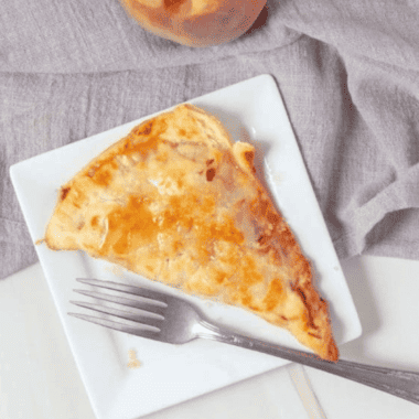 "Golden, crispy air fryer peach pie with a flaky crust and sweet peach filling on a white plate."