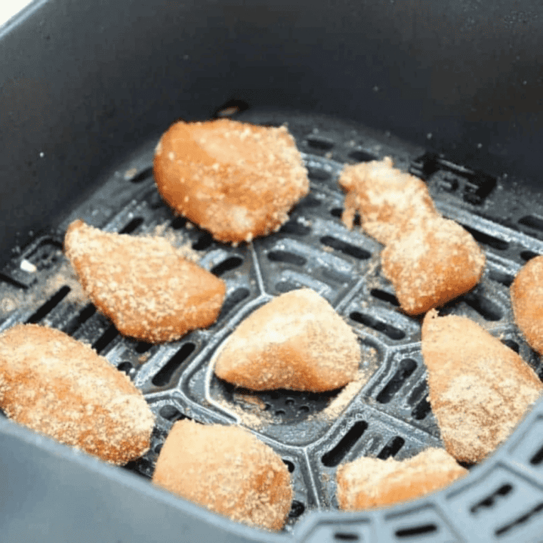 Coated chicken tenders arranged in a single layer in the air fryer basket.