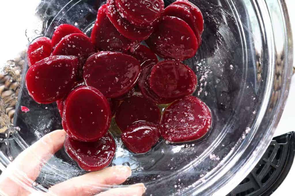 overhead: a bowl of beet slices with oil and seasonings