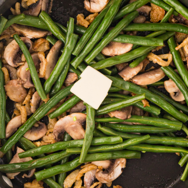 Green beans sizzling on an outdoor griddle with butter and spices melting over them
