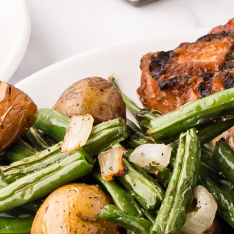 Fresh green beans cooking on a hot outdoor griddle with melted butter and spices