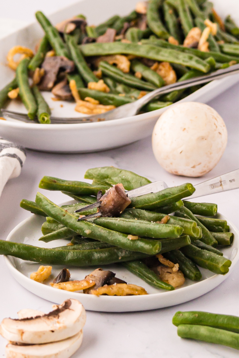 Close-up of green beans cooking on an outdoor flat-top griddle with butter melting