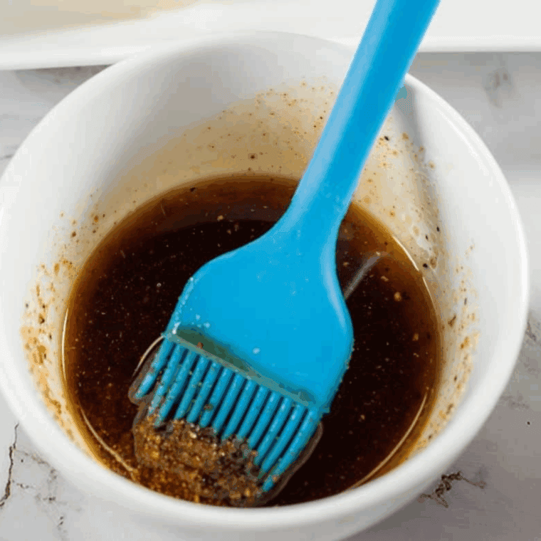 Mixing olive oil, lemon juice, and spices in a small bowl to create a flavorful corn rib marinade.