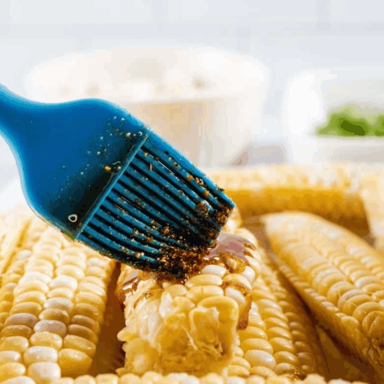 Cutting corn into quarters and brushing with seasoned oil for flavorful corn ribs.
