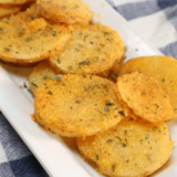 Golden crispy parmesan crusted potatoes in air fryer basket, freshly cooked and ready to serve.