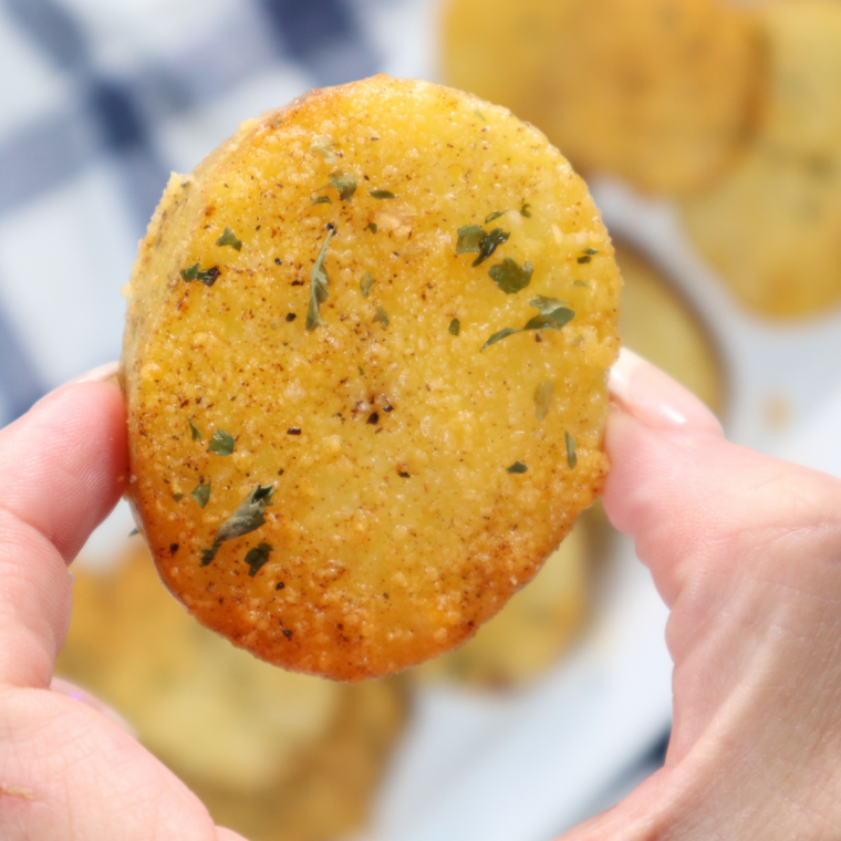 Golden parmesan crusted potatoes cooked in an air fryer with crispy edges, soft fluffy centers, and a cheesy coating served on a plate.
