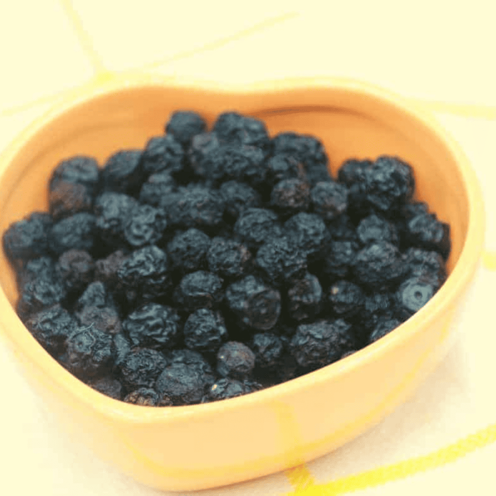 a small orange heart-shaped bowl full of dehydrated blueberries