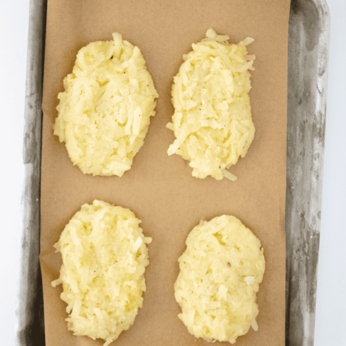 Hash brown patties arranged in a single layer in the air fryer basket, lightly oiled and ready to cook at 370°F.