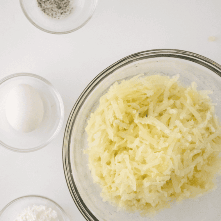 Hands shaping seasoned shredded potatoes into a firm patty, ready for cooking.