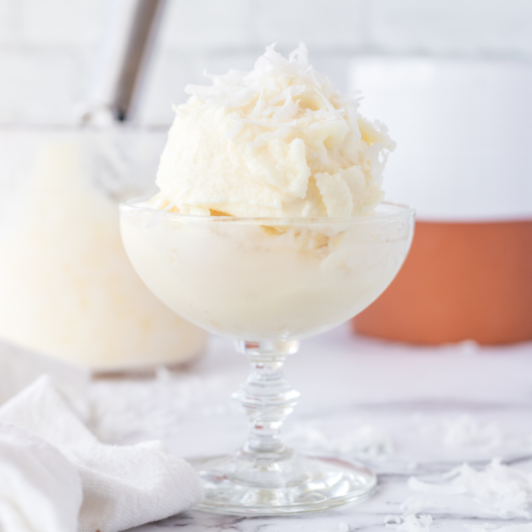 Creamy scoop of Ninja Creami pineapple sorbet in a bowl with fresh pineapple chunks.