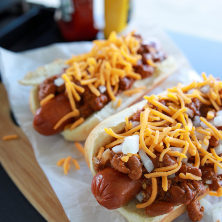 Hot dogs reheating in an air fryer basket with lightly crisped edges and evenly warmed centers ready to serve.