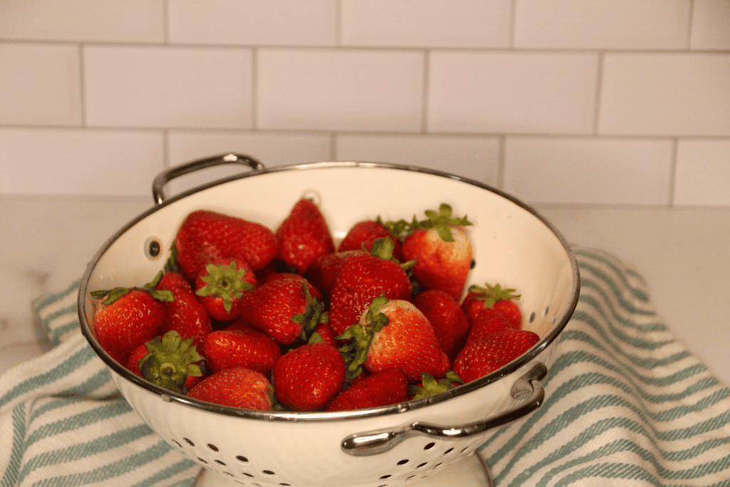 a white colander with fresh strawberries