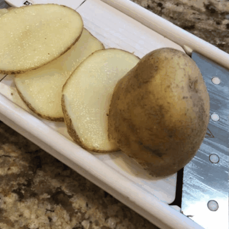 Slicing the potatoes with a mandoline slicer.