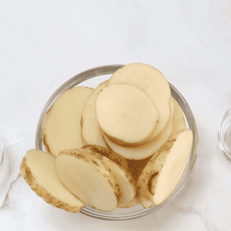 Sliced potatoes in a mixing bowl.