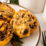 Four Cuban picadillo stuffed peppers in an air fryer basket, filled with ground beef, green olives, and raisins