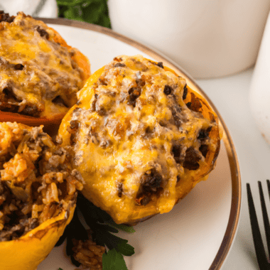 Four Cuban picadillo stuffed peppers in an air fryer basket, filled with ground beef, green olives, and raisins