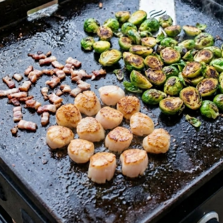 Scallops sizzling on a hot flat top griddle forming a golden brown crust without being moved.