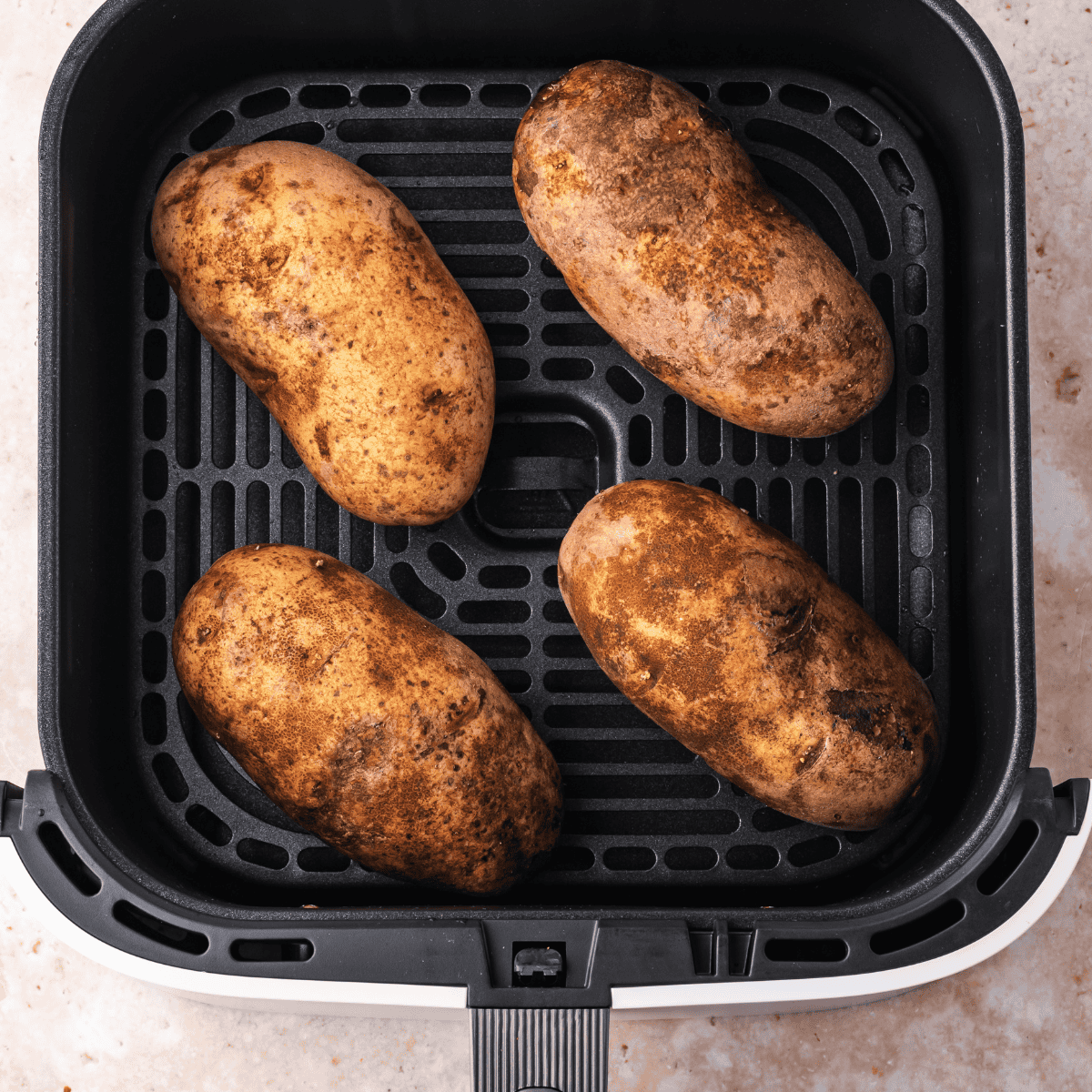 Baked potato in the air fryer basket, ready for cooking.