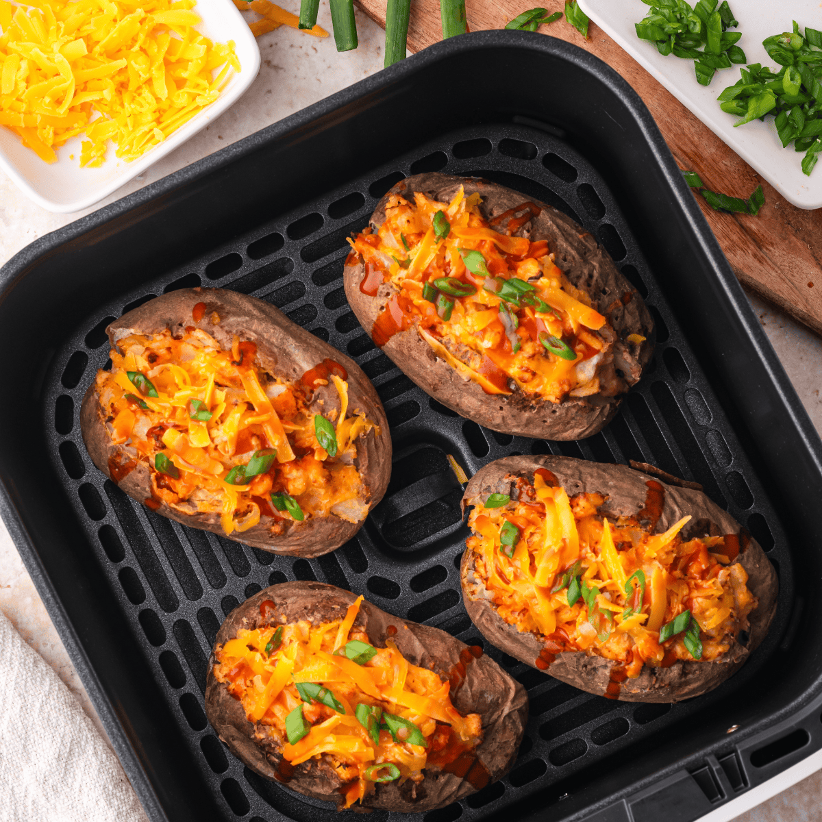 Cooked baked potatoes in the air fryer basket.