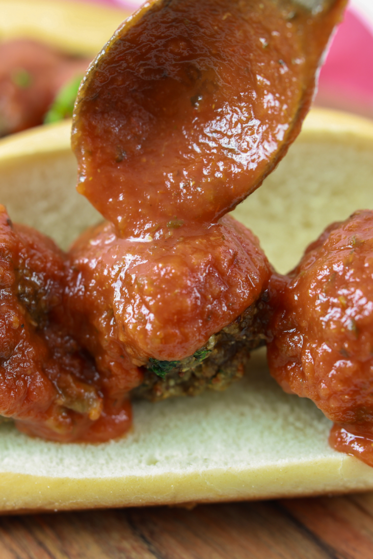 Extra marinara spooned over the finished meatball sub before the Parmesan