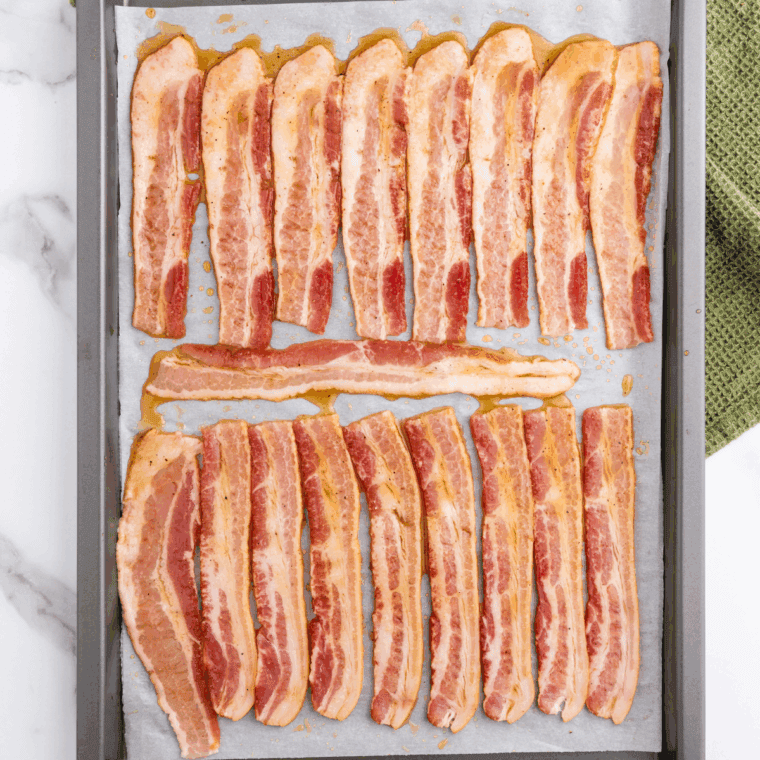 Thick-cut bacon slices laid out in a single layer on baking sheet.