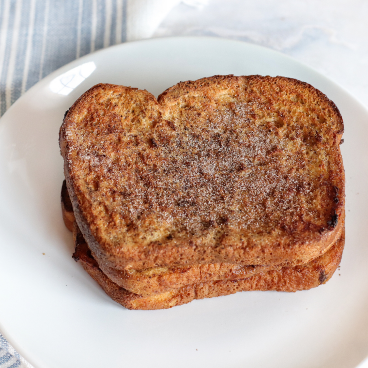 Stack of French toast slices on a plate drizzled with maple syrup