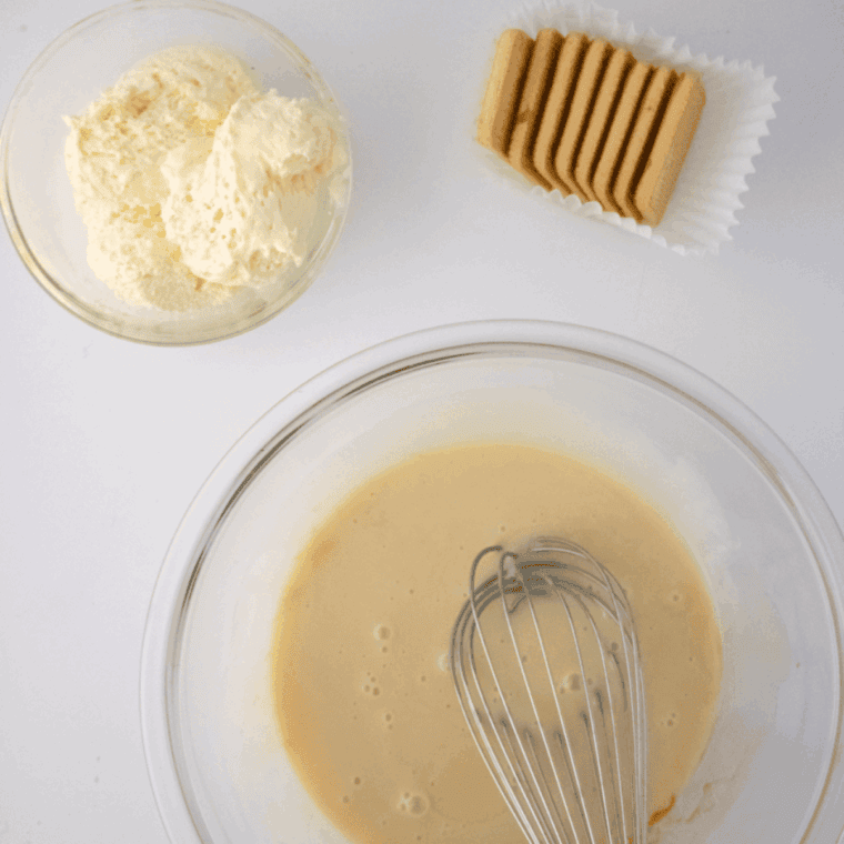 Mixing softened cream cheese, cocoa powder, sugar, and vanilla in a bowl, then folding in heavy cream and milk until smooth and blended.