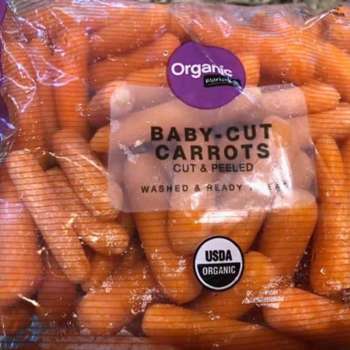 "Ingredients for Air Fryer Baby Carrots arranged on a table, including fresh baby carrots, olive oil, and seasonings."