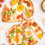 Air Fryer Breakfast Flatbread Pizza topped with eggs, cheese, and veggies.