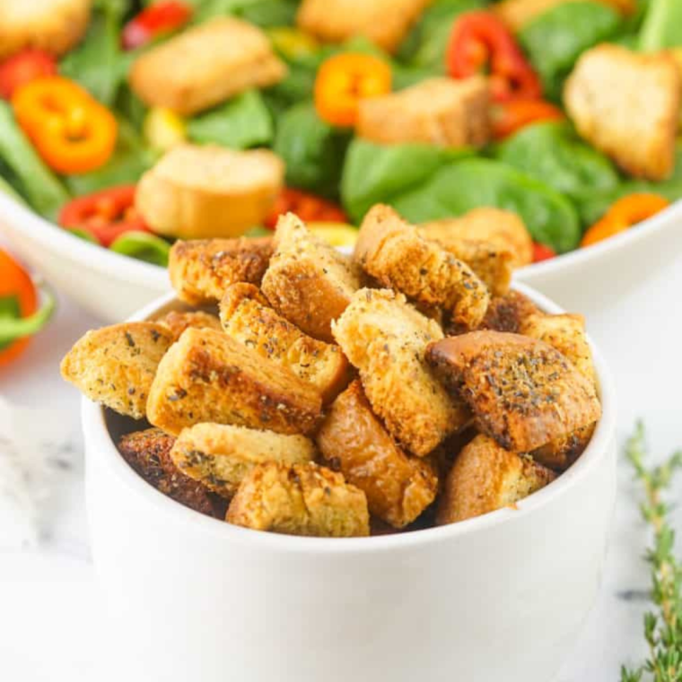 Plate of Croutons in front of a large garden salad.