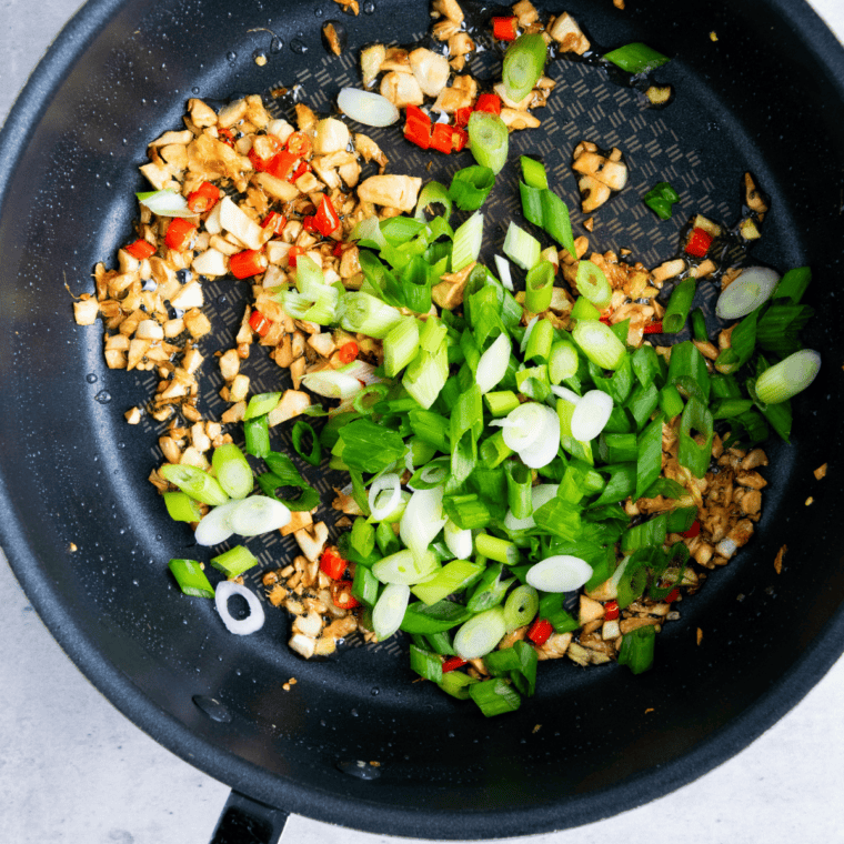 Sliced garlic and red chili frying in oil in a small skillet until golden