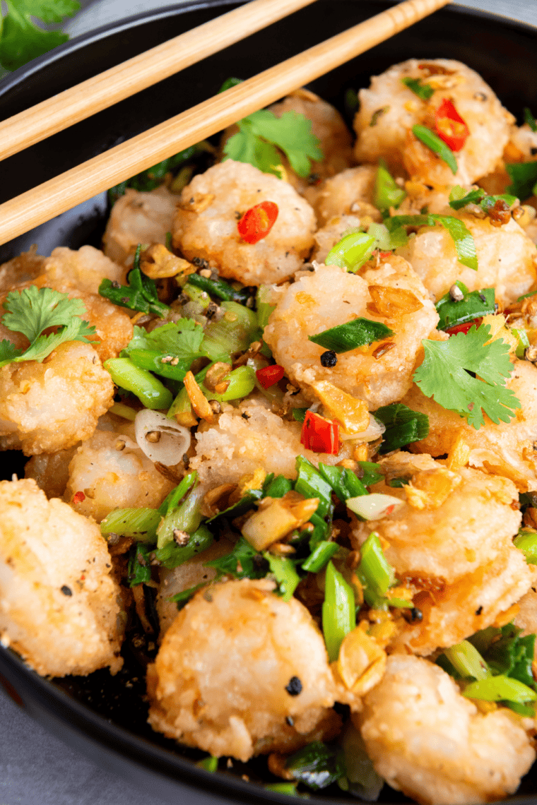 Salt and pepper shrimp tossed with crispy garlic and chilies on a serving plate