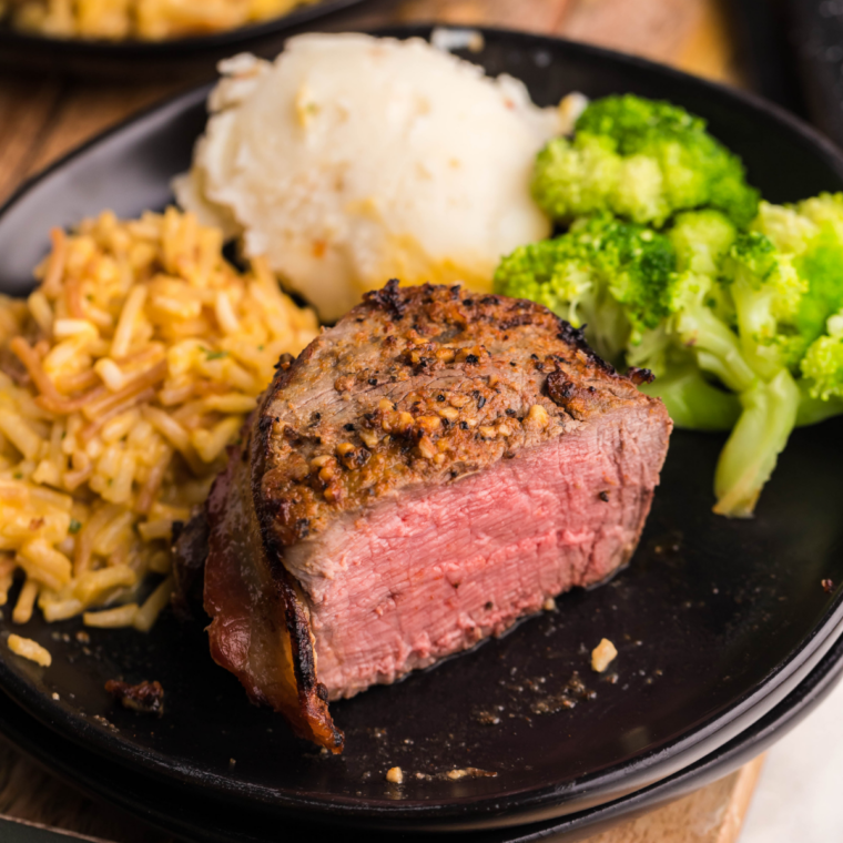 Juicy Blackstone filet mignon steak searing on a hot griddle with butter and herbs