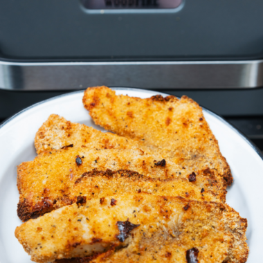 Blackstone tilapia fillets sizzling on a hot griddle with golden brown seasoning crust