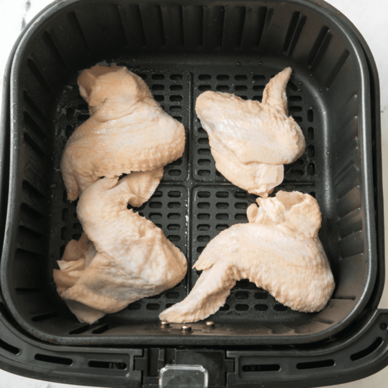 Raw chicken wings in the air fryer basket.