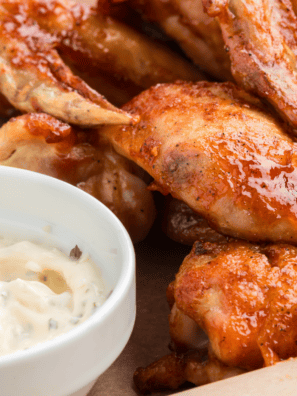 Bowl of homemade copycat Hooters wing sauce with a whisk resting on the side