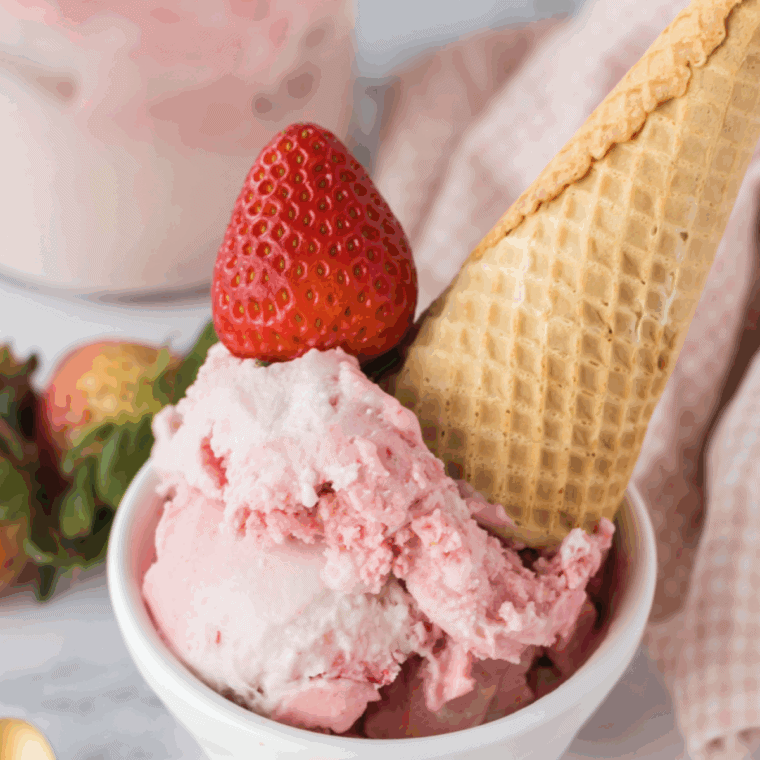Bowl of creamy strawberry ice cream made with condensed milk, topped with fresh strawberry slices.