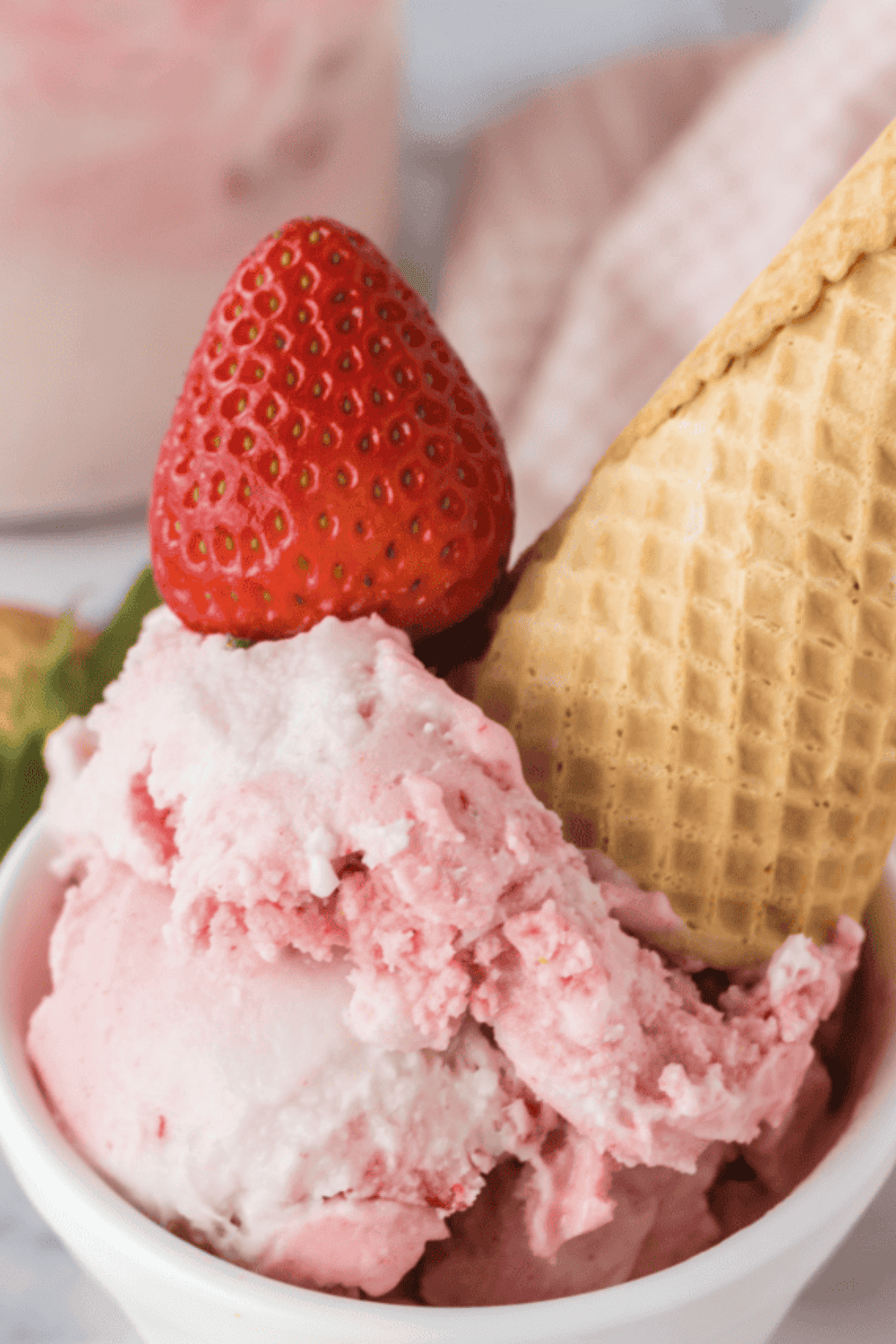Bowl of creamy strawberry ice cream made with condensed milk, topped with fresh strawberry slices.