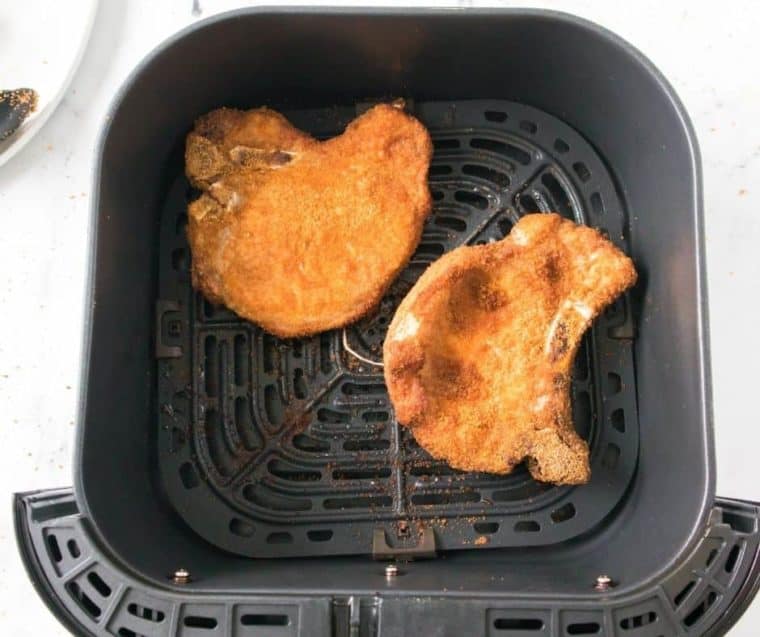 Top view of air fryer breaded pork chops in an air fryer basket. 