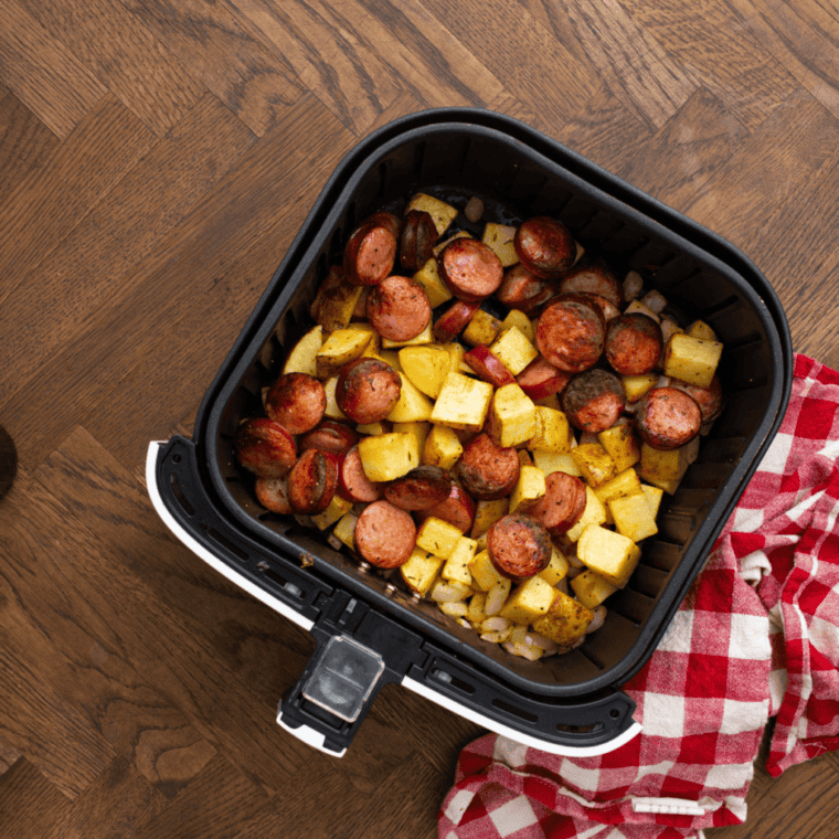 top view of cooked air fryer sausage and potatoes in an air fryer basket. 