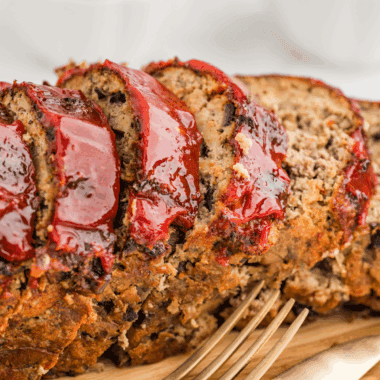 A colorful platter featuring a variety of savory side dishes served alongside a classic meatloaf.